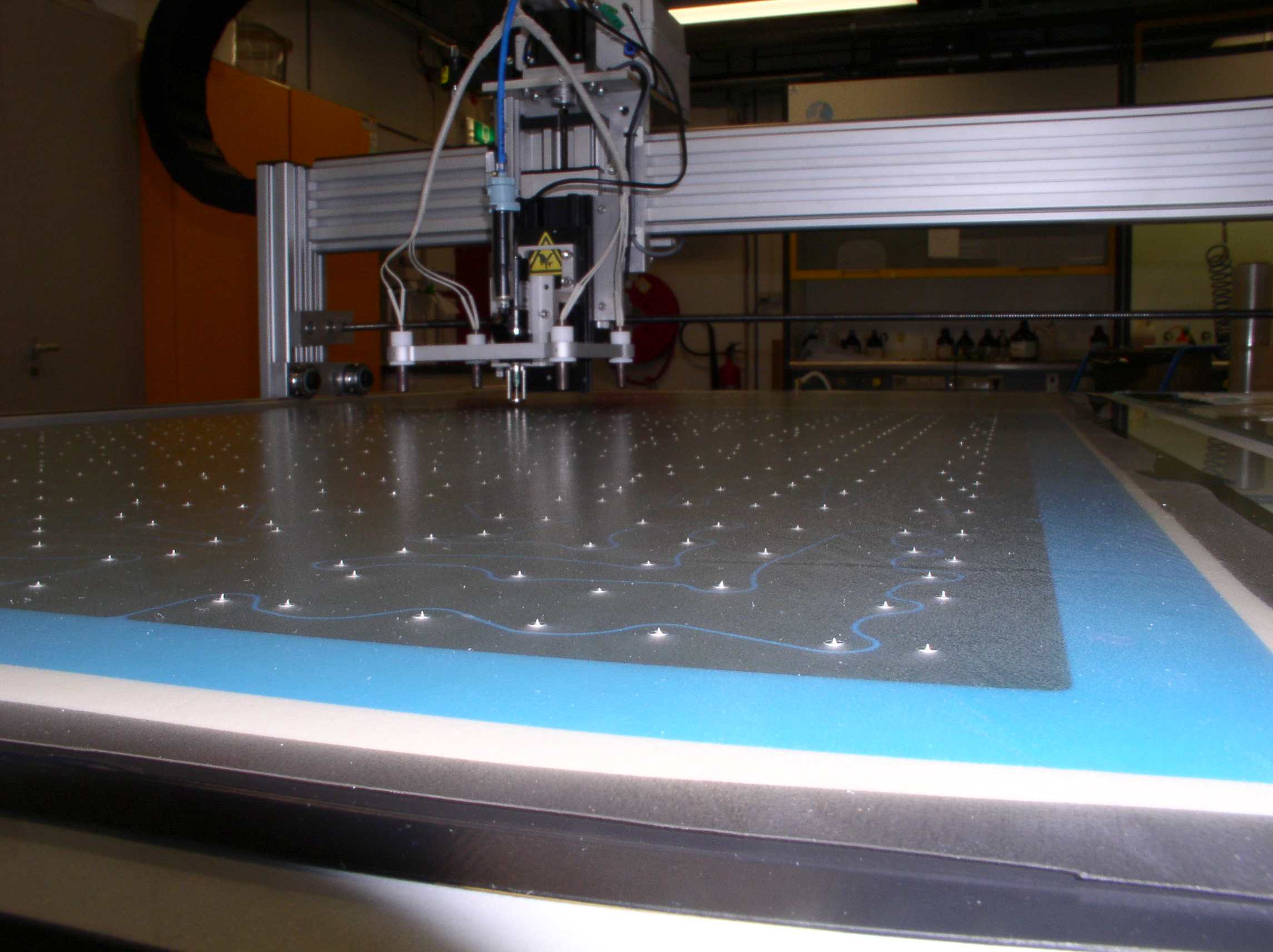 Automated dispensing of conductive adhesive for metallisation-wrap-through (MWT) solar panel